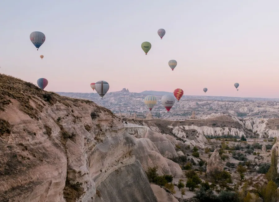 Hot-air balloons flying above Cappadocia's rock valleys at sunrise